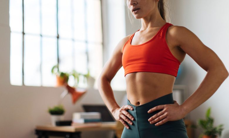 A woman with toned abs placing her hands on her hips