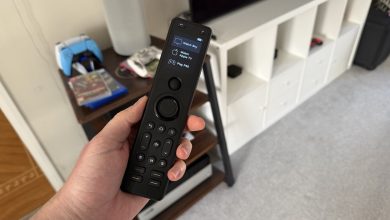 A photo of someone holding a Sofabaton X1S remote control in a living room