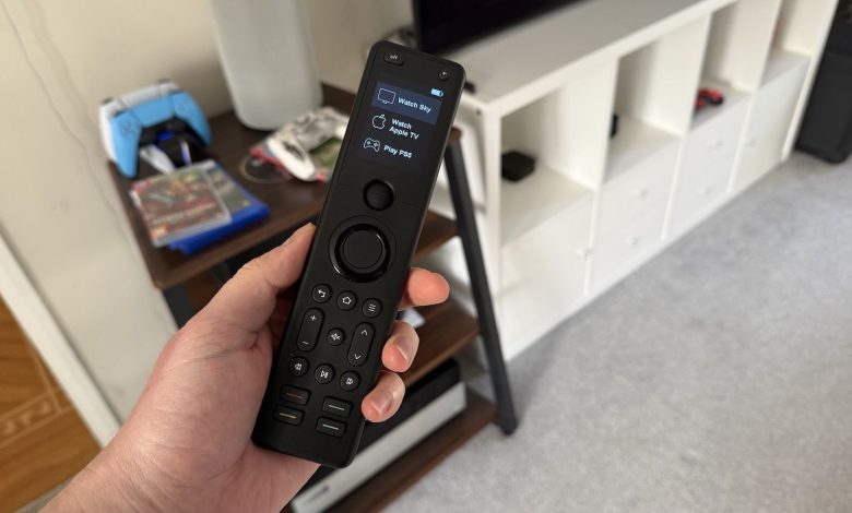 A photo of someone holding a Sofabaton X1S remote control in a living room