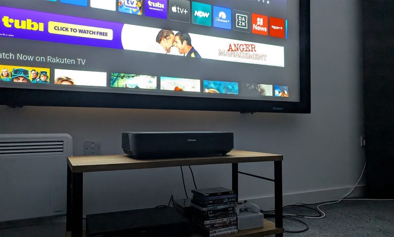 A Hisense PL2 UST projector in operation. It is positioned on a wooden bench and the interface is visible being projected onto a screen.