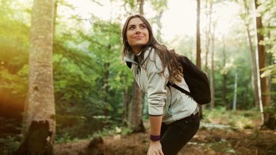 Woman in a forest wearing backpack and walking in nature smiling