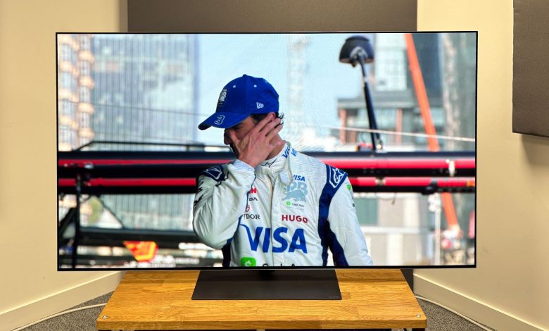 The 65-inch LG G5 OLED TV pictured on a wooden rack. On the screen is a still from Netflix F1 series Drive to Survive.