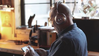 A man wearing a pair of Écoute TH1 over-ear headphones while operating a tablet.