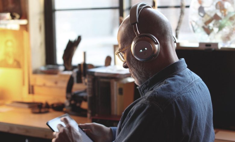 A man wearing a pair of Écoute TH1 over-ear headphones while operating a tablet.
