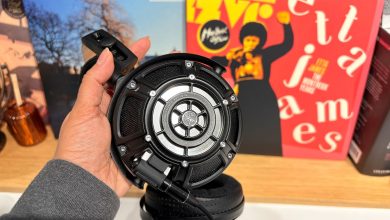 Yamaha YH-4000 open-back wired headphones held in hand in front of busy bookshelf