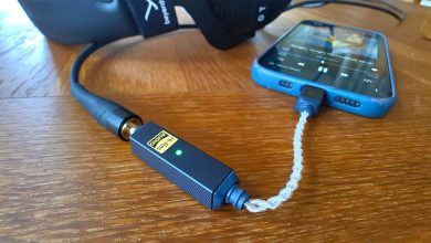 iFi Go Link 2 DAC on wooden table connected to headphones and smartphone