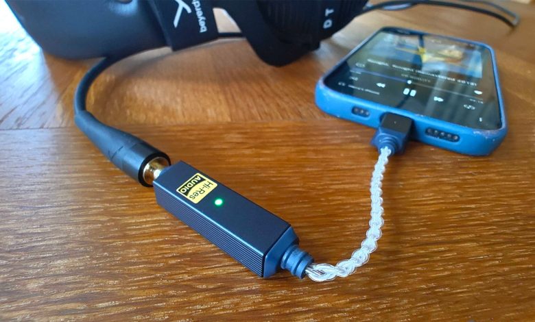 iFi Go Link 2 DAC on wooden table connected to headphones and smartphone