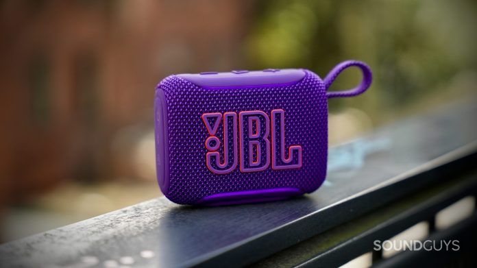 JBL Go 5 purple Bluetooth speaker resting on a metal railing outdoors