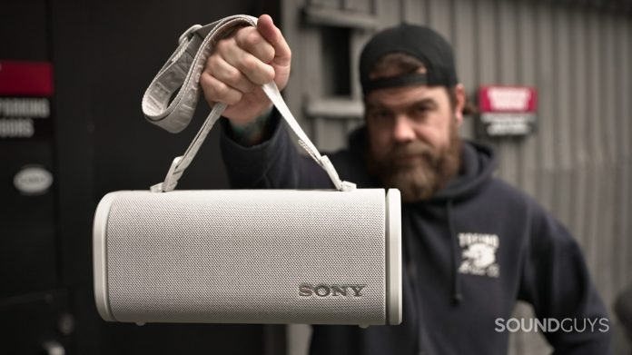 A man holding a Sony ULT Field 5 speaker by its shoulder strap.