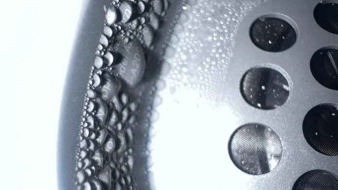 Extreme close-up of condensation inside an Apple AirPods Max ear cup, highlighting dense water droplets forming along the interior wall beside the speaker grille.